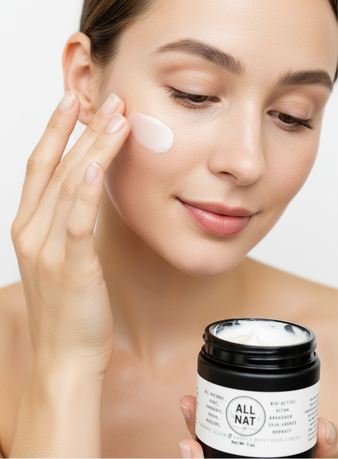 Woman applying cream to her face with a jar of All Nat cream in the foreground.